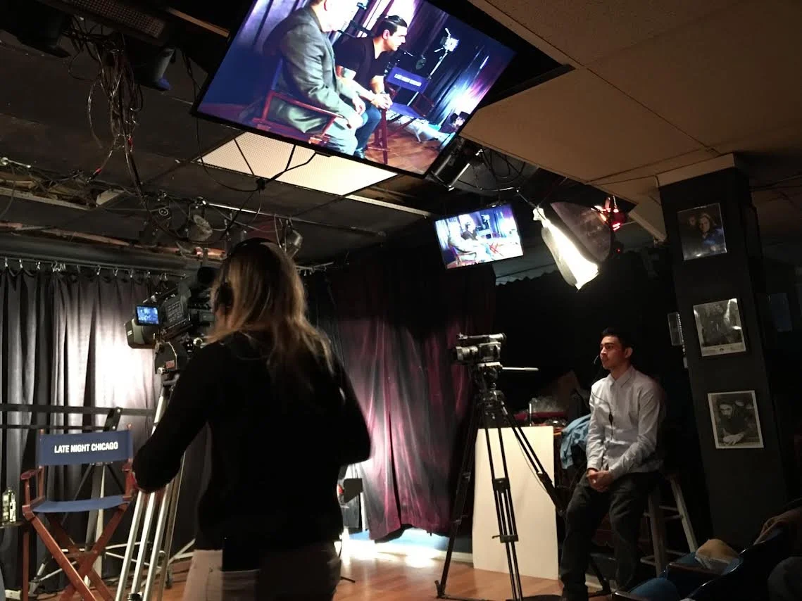 Silhouette of a person operating a professional video camera.