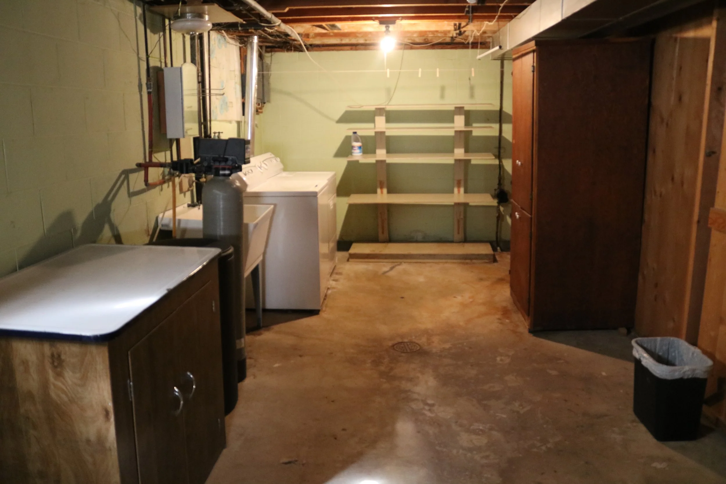 Basement laundry room with washer, cabinets, and storage shelves.