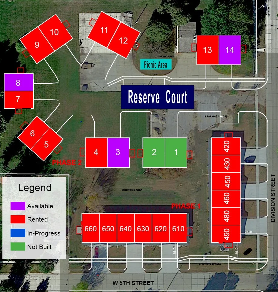 A site plan of a housing development shows various lot layouts with colors indicating availability: purple for available lots, red for rented, blue for in-progress construction, and green for not built. The plan includes sections labeled Reserve Court, picnic area, detention area, and parking spaces, with streets along W 5th Street and Division Street. The lots are numbered, with a large row of red lots numbered 610 to 660, and other smaller clusters surrounding the reserve court.