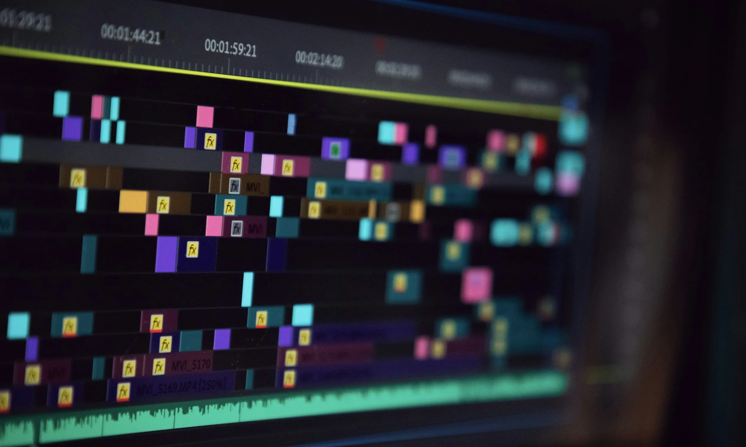 Close-up of a video editing timeline on a computer screen, featuring multiple colorful tracks and clips used for editing a video.