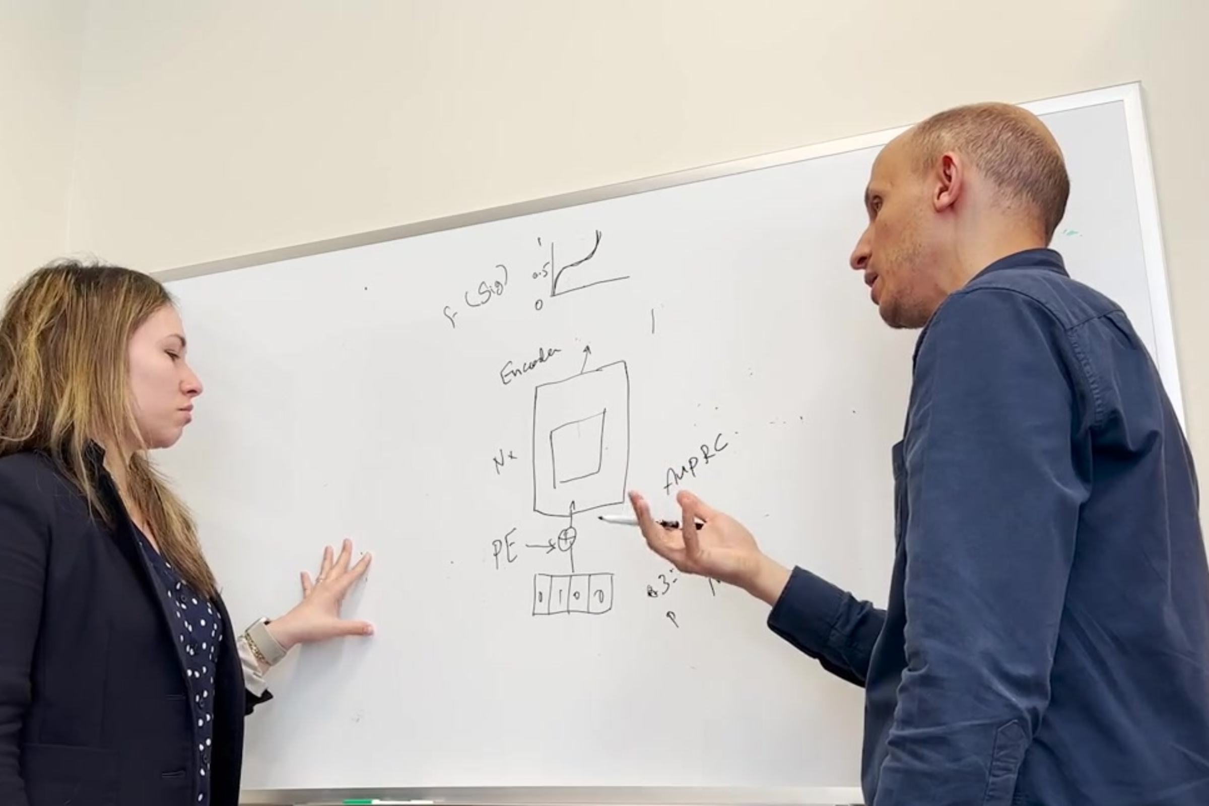 Dr. Noam Auslander and lab partner discuss AI research written on whiteboard