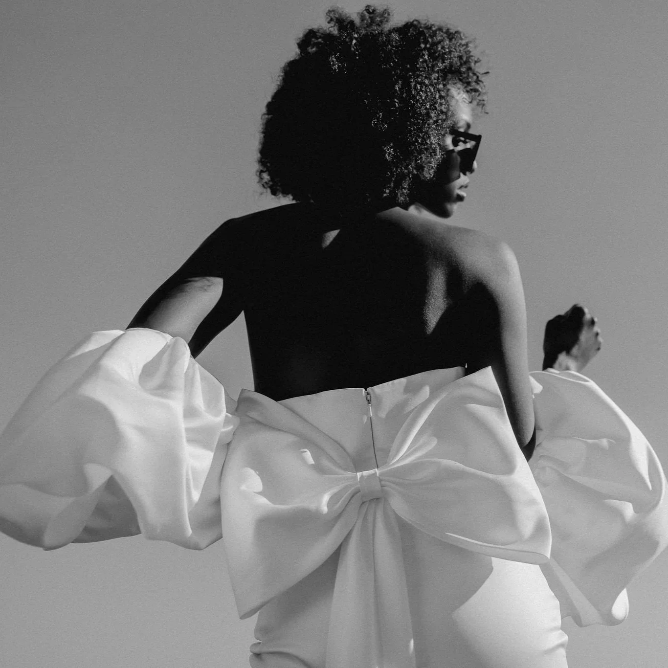 Model wearing a Lover Collection off-shoulder dress with voluminous sleeves, black and white