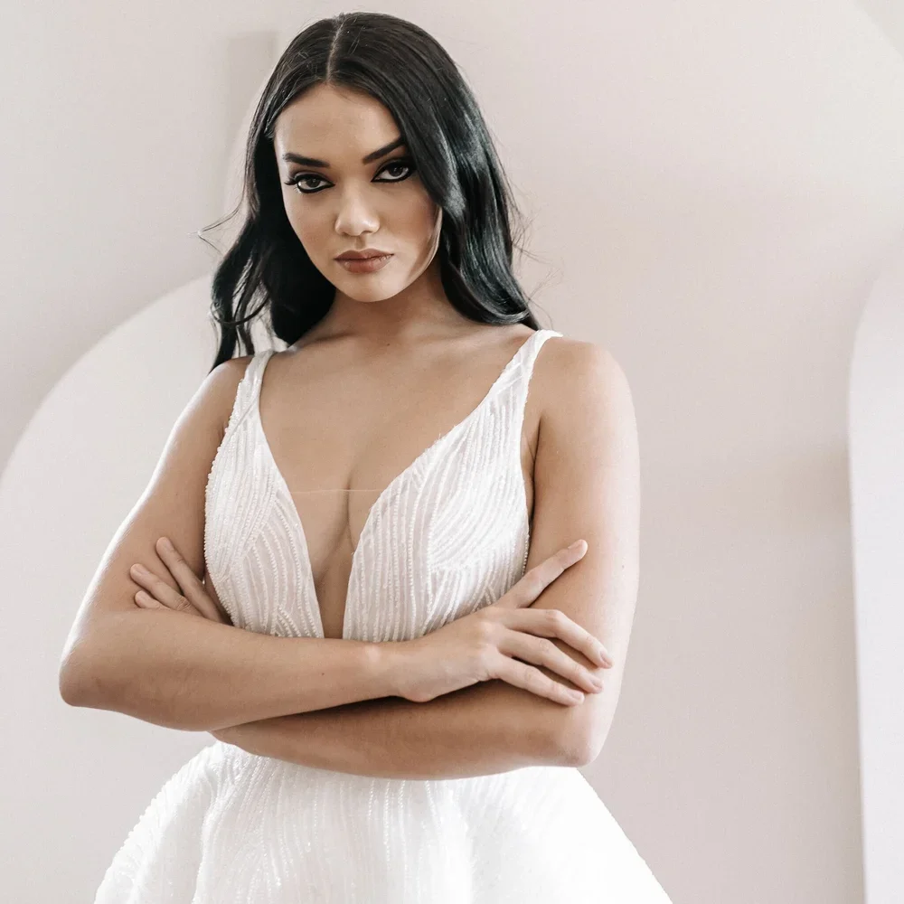 Model wearing a sleeveless deep V-neck wedding dress from the Her Collection