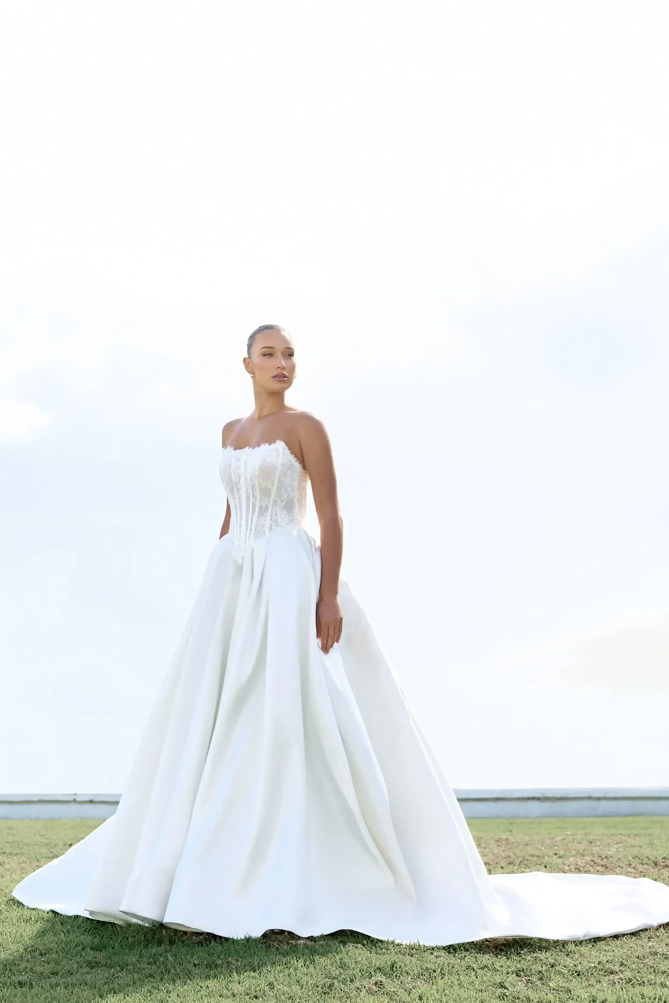 Model wearing an Isabella strapless white wedding gown with lace bodice outdoors