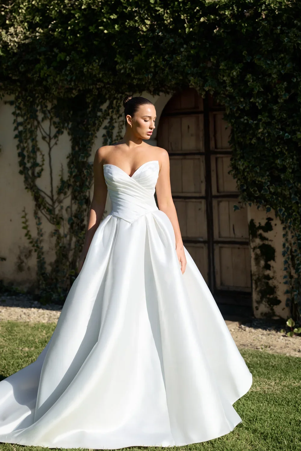 Model wearing a strapless Camilla white ball gown wedding dress outdoors