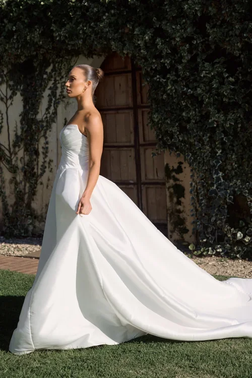 Model wearing a Camilla strapless white wedding dress with long train outdoors