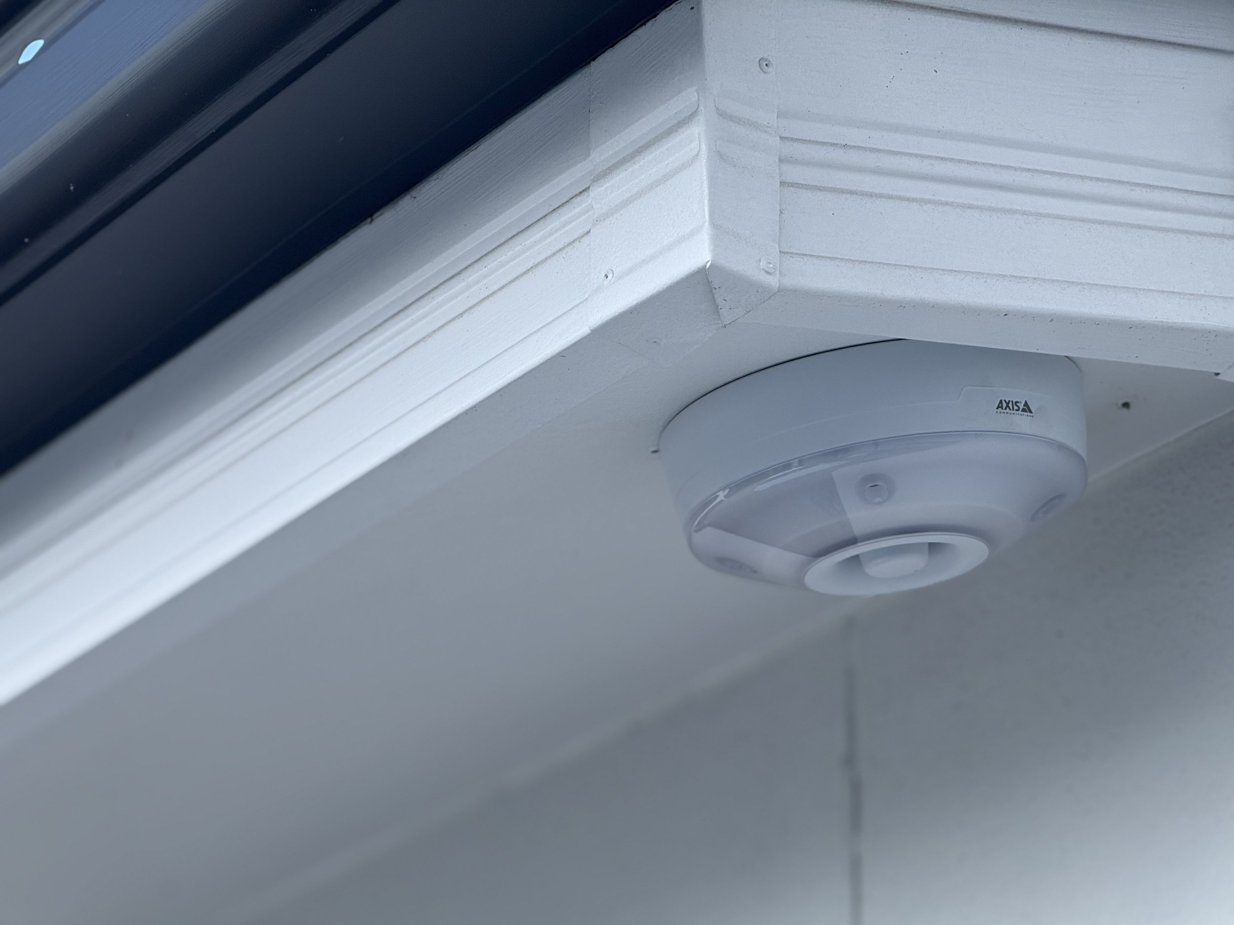 Outdoor security camera mounted under a roof eave.