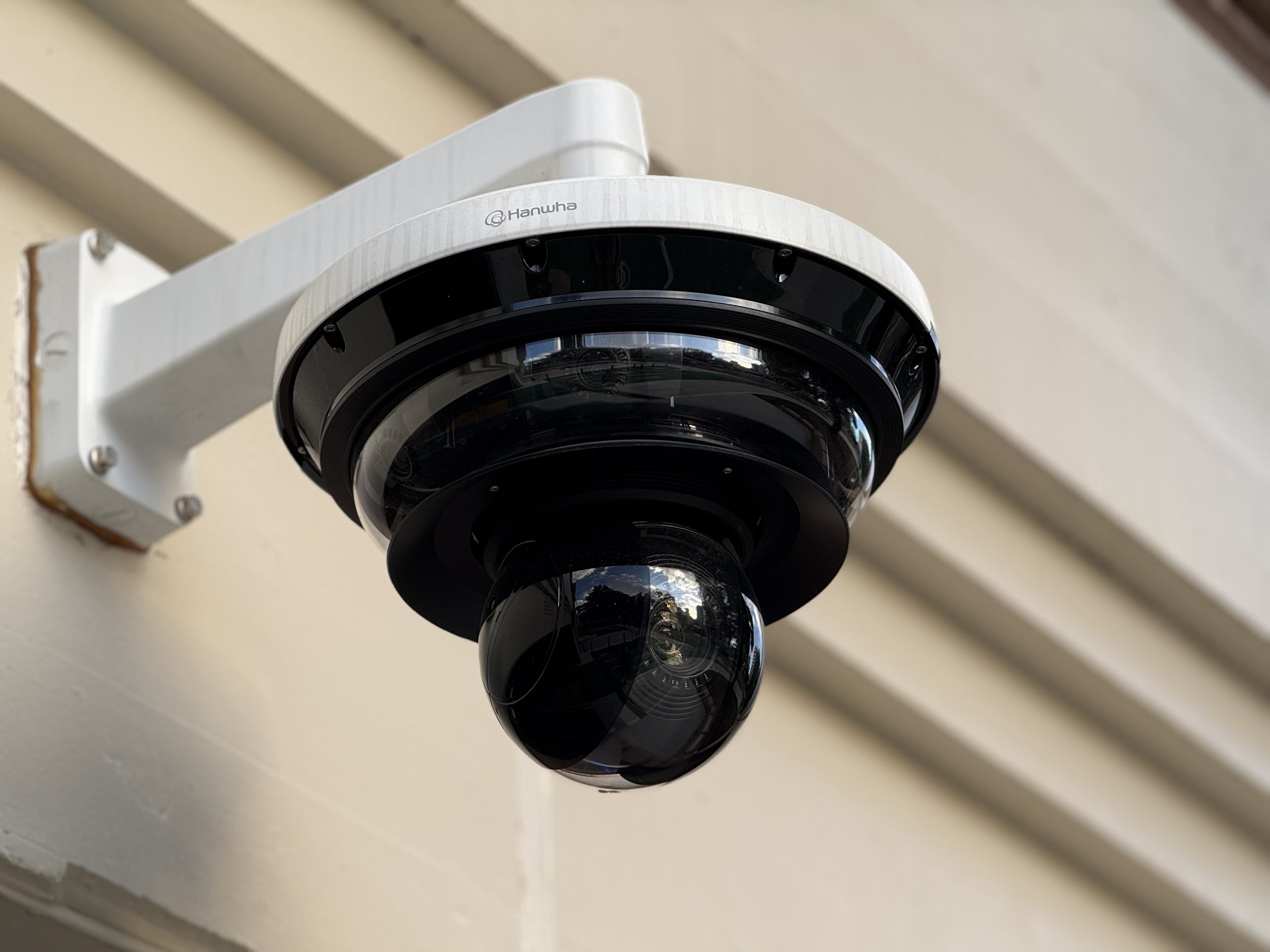 Outdoor security camera mounted on a wall, featuring a dome design.