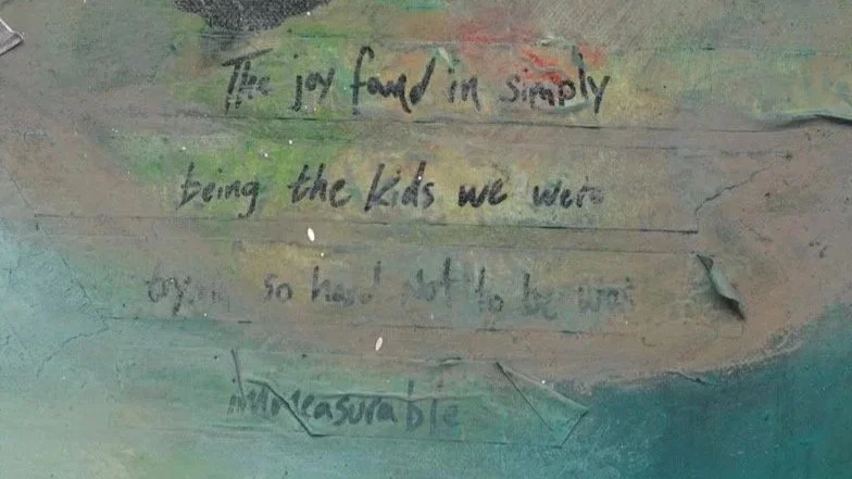 A close up detail photo of “Becoming Memories” artwork. A wall with faded and peeling paint showing handwritten text with some words obscured or difficult to read.