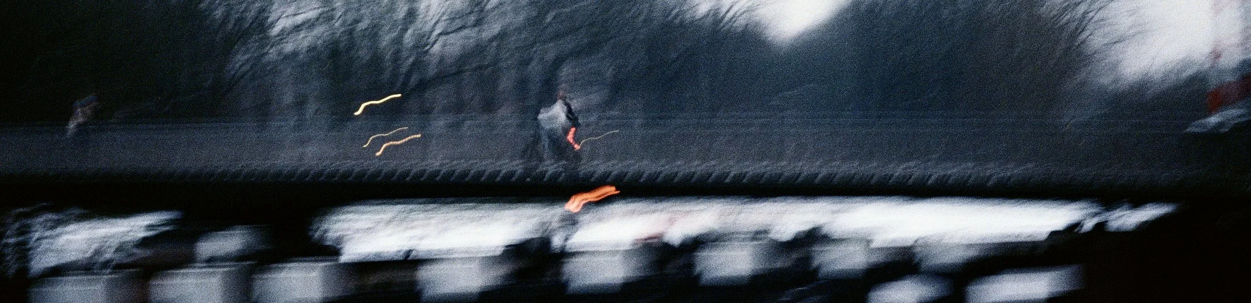 Blurred photo of a cyclist riding across a bridge on a snowy day.