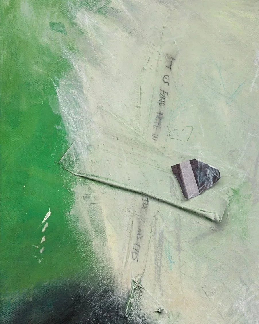 A close up detail photo of “Becoming Memories” artwork. A close-up of a dusty green surface with a piece of torn paper and a small piece of glass or rock.