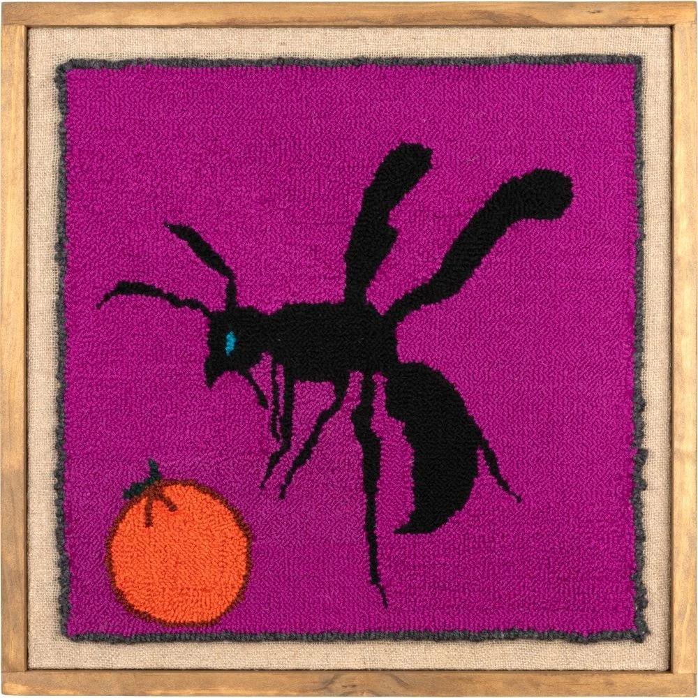 a punch needle fiber art piece of a wasp and an orange, rendered in saturated pinks, oranges, and blacks.
