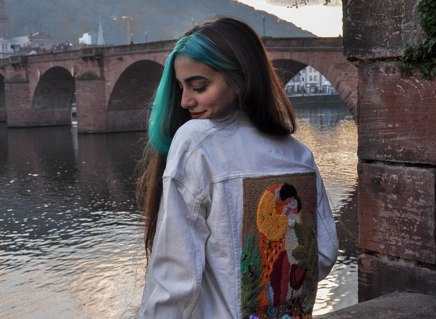 This jacket pays tribute to the painting &lsquo;The Kiss&rsquo; by Gustave Klimt. The panel on its back, made with the punch needle technique, reinterprets the artwork with clear forms and bold colors, emphasizing the tenderness and richness, which a