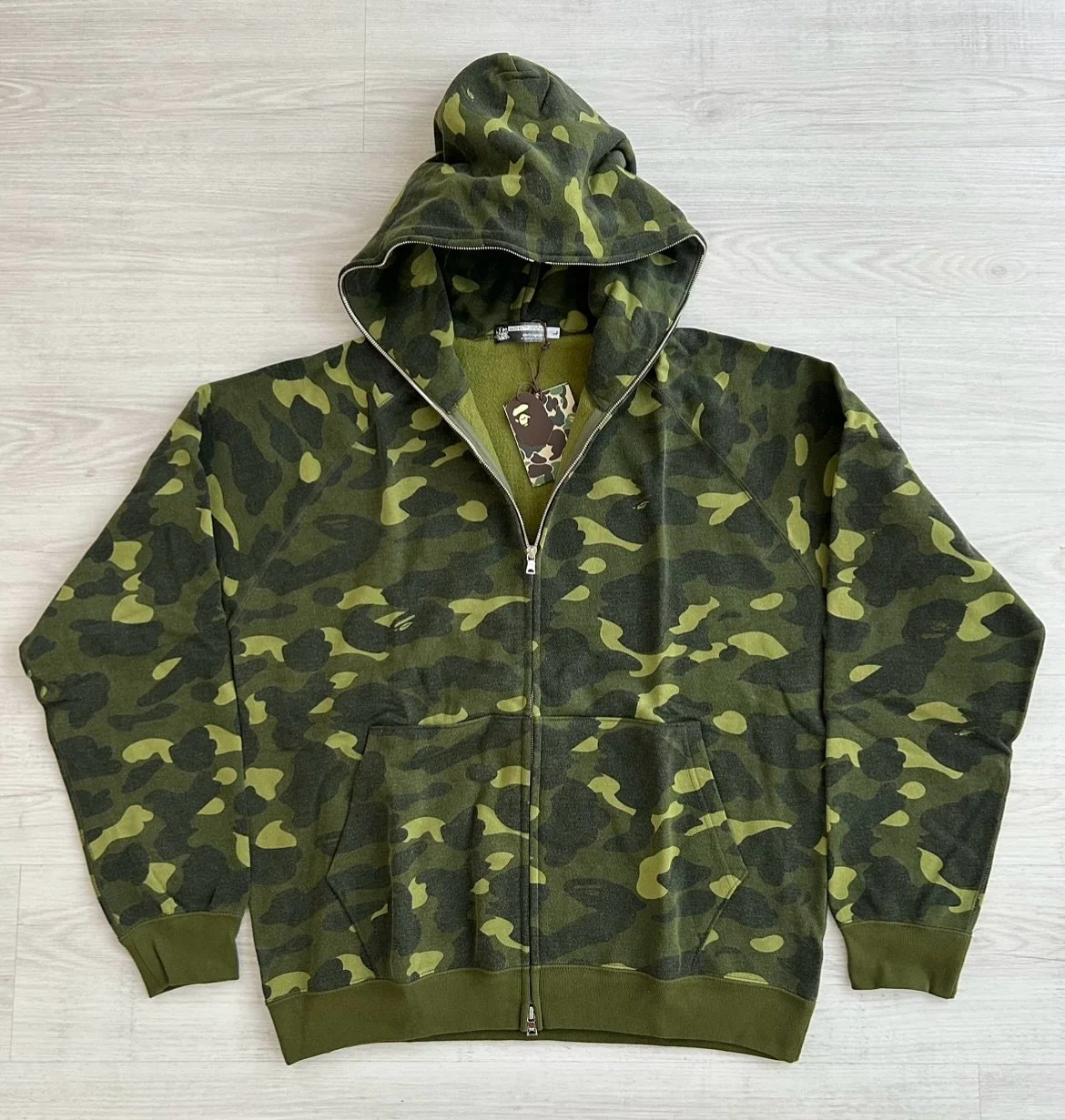 An official 2005 A Bathing Ape &ldquo;Olive 1st camo&rdquo; fullzip hoodie.

The colorway on this sweater was the camos premiere and also a &ldquo;Nigo&rsquo;s Favorite Shop&rdquo; exclusive release. This grail could only be obtained as a BAPE card m