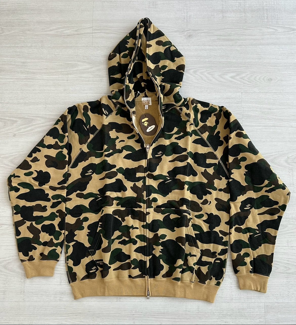 First edition original A Bathing Ape 1st yellow camo fullzip hoodie on display.

The sunshine yellow base gives a playful twist to the brand&rsquo;s early camouflage motif, turning a utilitarian pattern into a streetwear icon.

Design wise, the 1st c