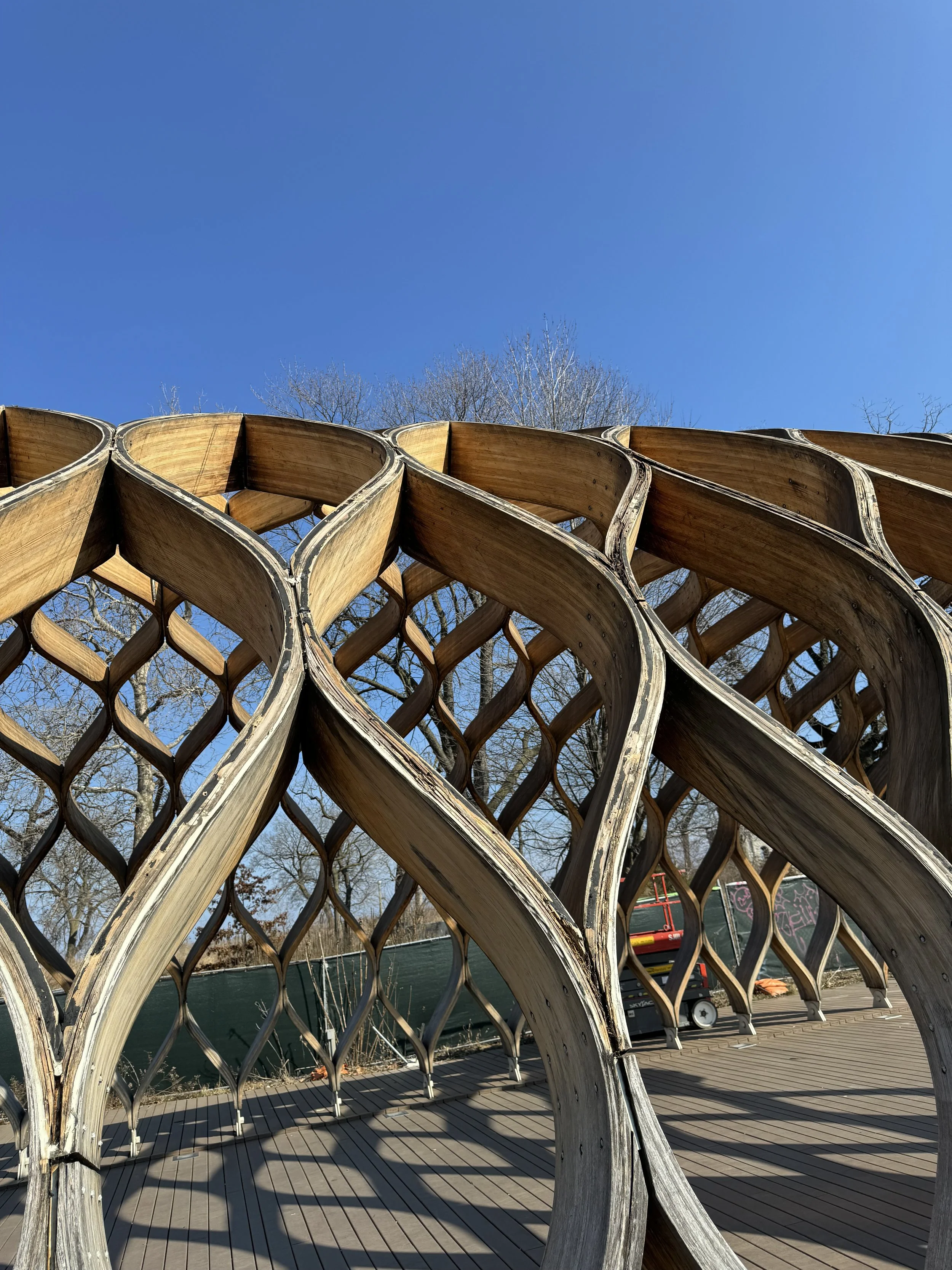 Architectural structure with wooden lattice design under clear blue sky.