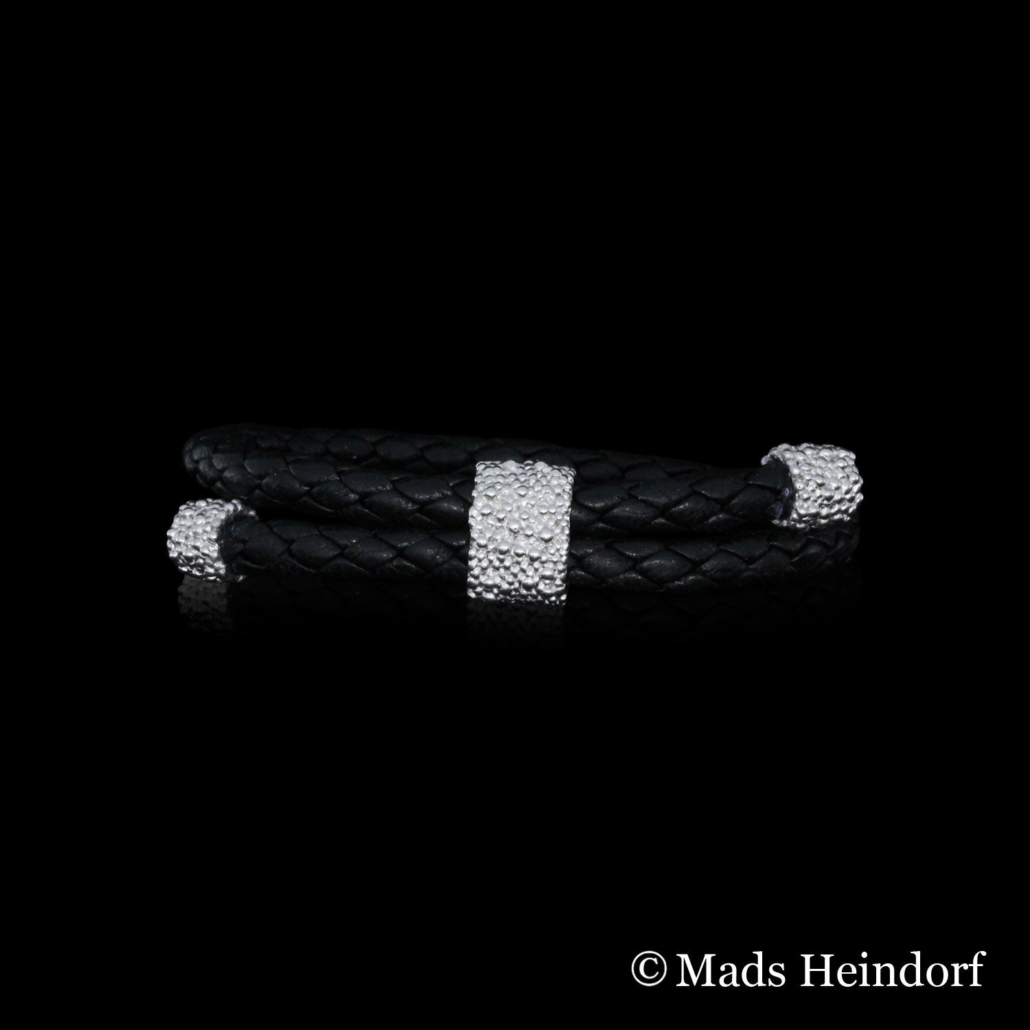 Håndlavet armbånd af sterling sølv med sort flettet lædersnor fra kollektionen Myriader af Guldsmed Heindorf.