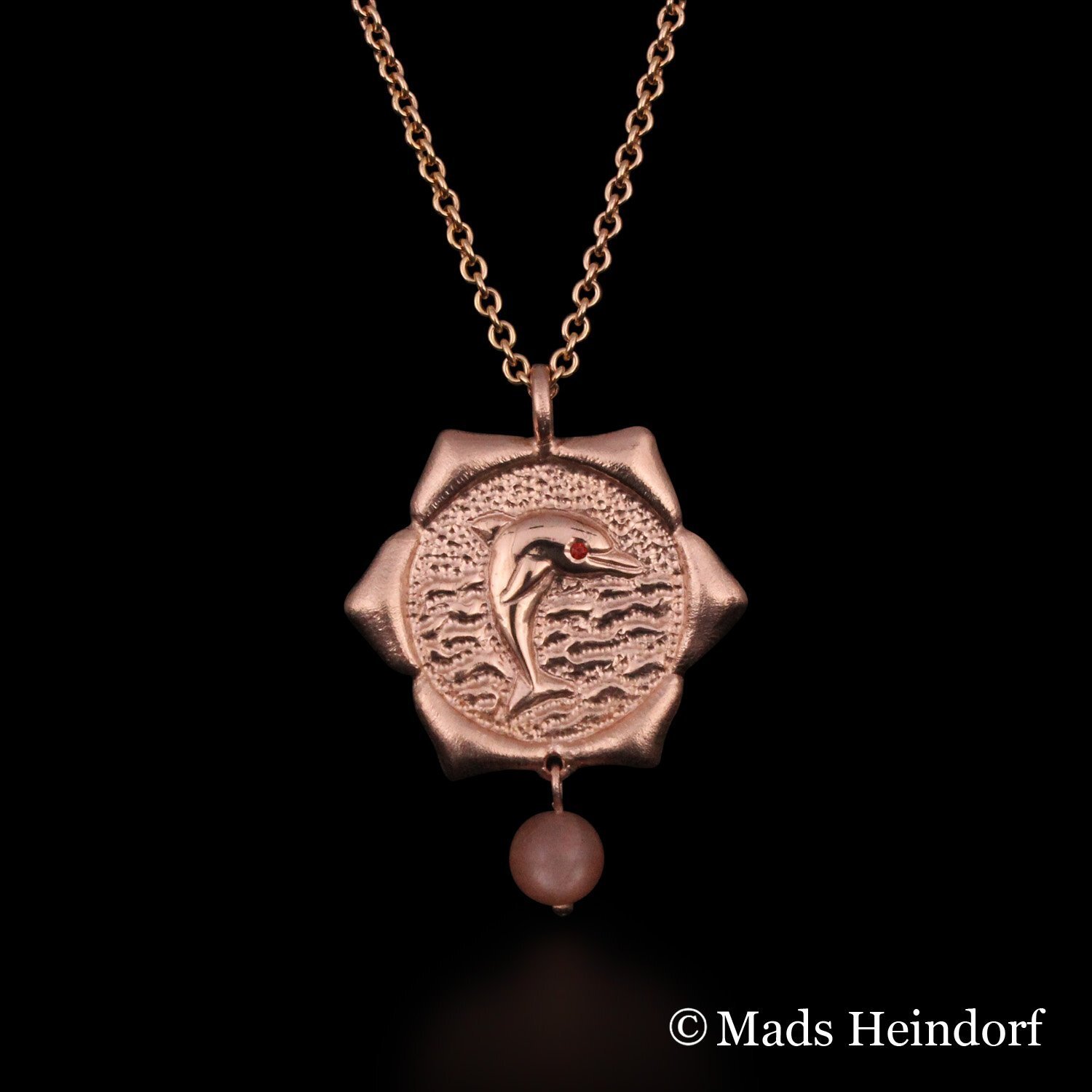 Harachakra er et håndlavet halssmykke af sterling sølv, forgyldt rosa, med 2 facetslebne orange safirer og 1 brun stenperle af solsten fra kollektionen Chakra af Guldsmed Heindorf.
