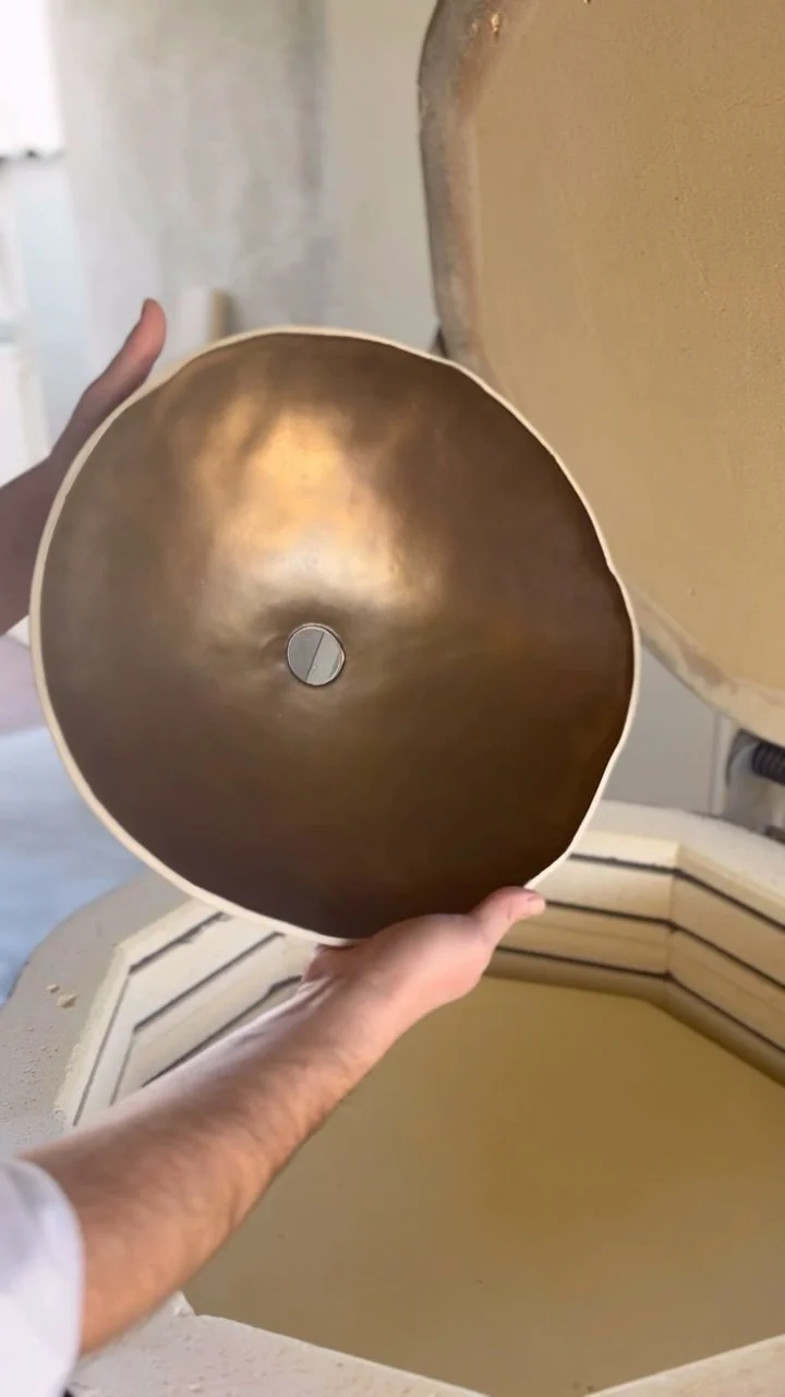 Steve Abate holding a bronze glaze and raw clay domed ceramic light shade straight out of the kiln.