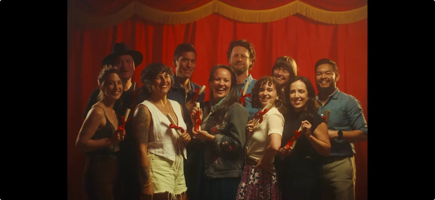 A cast of country dancers posed together in front of a red stage curtain on the Emily Nenni Movin' Shoes video shoot