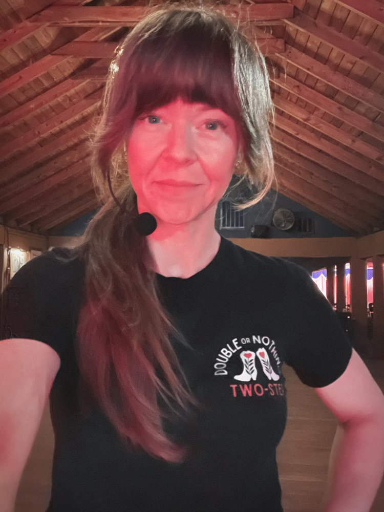 Vanessa Vaught in a Double or Nothing Two-Step shirt wearing a headset microphone inside a Texas dance hall