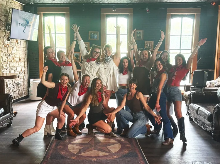 Bachelorette party celebrating with arms up at an Austin honky-tonk line dance lesson