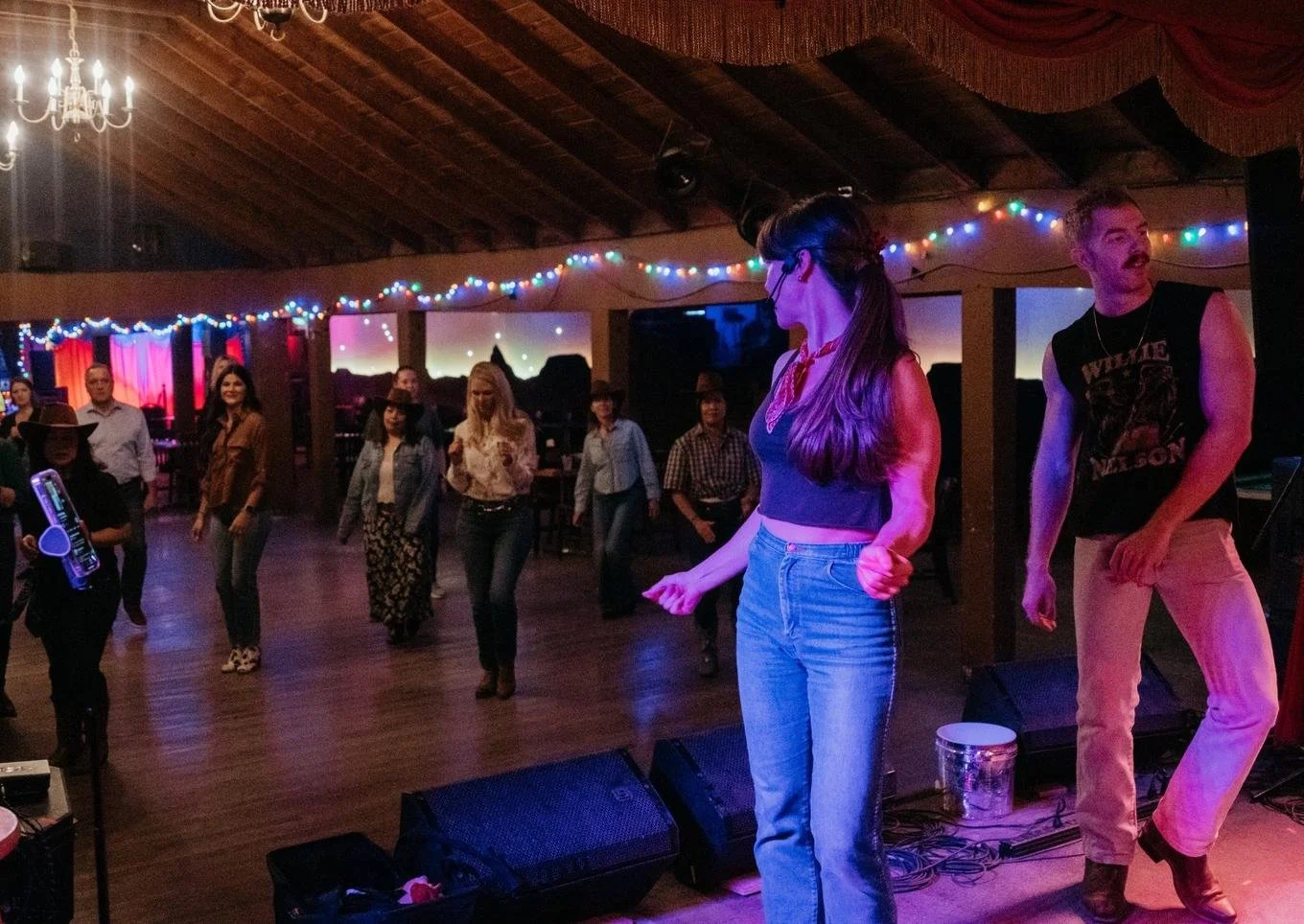A line dance lesson in progress under string lights at Sagebrush in South Austin