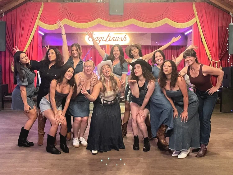 Bachelorette group with arms raised on the Sagebrush honky-tonk stage in Austin
