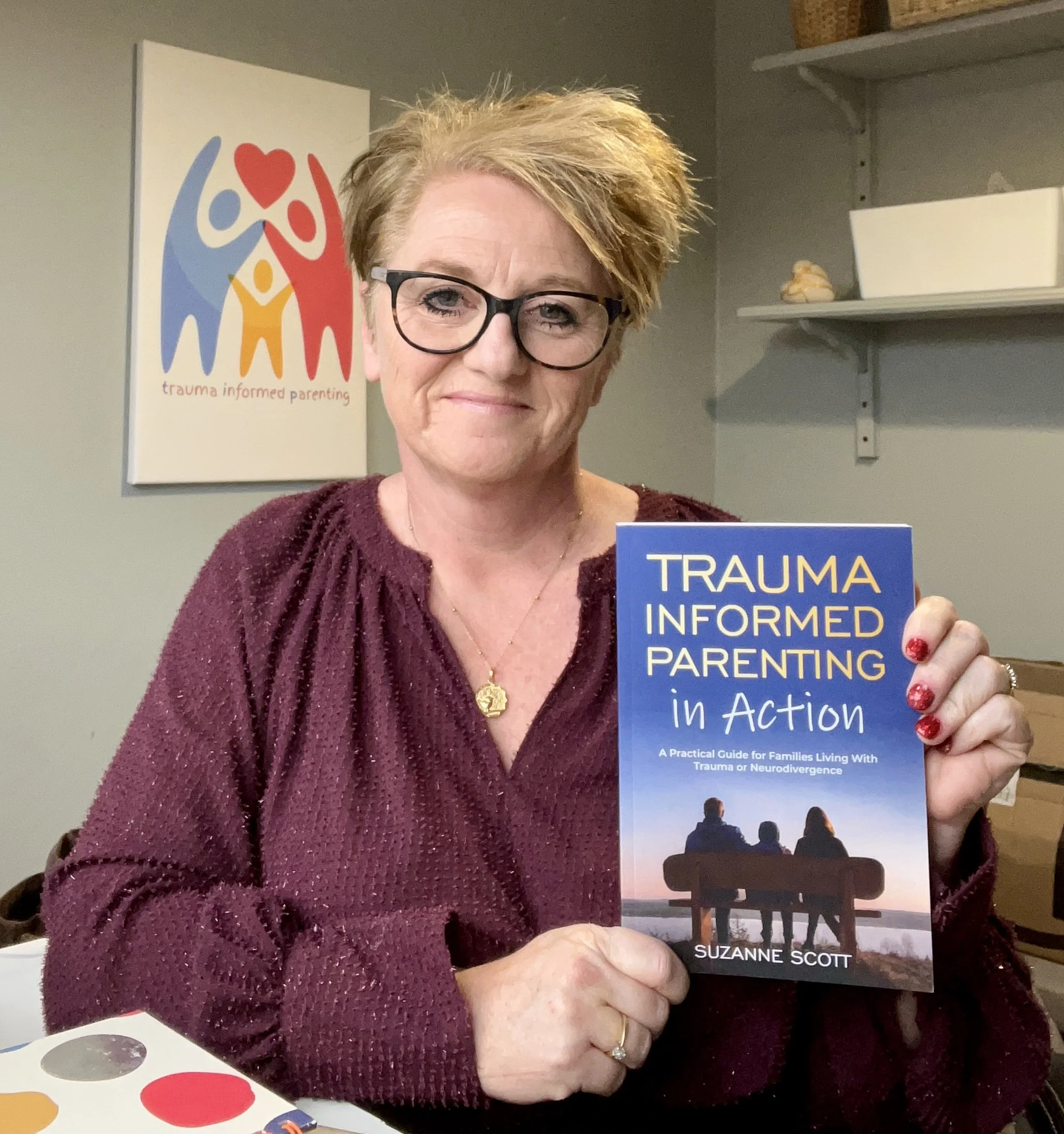 A Photo of Suzanne holding a copy of her book Trauma Informed Parenting in Action