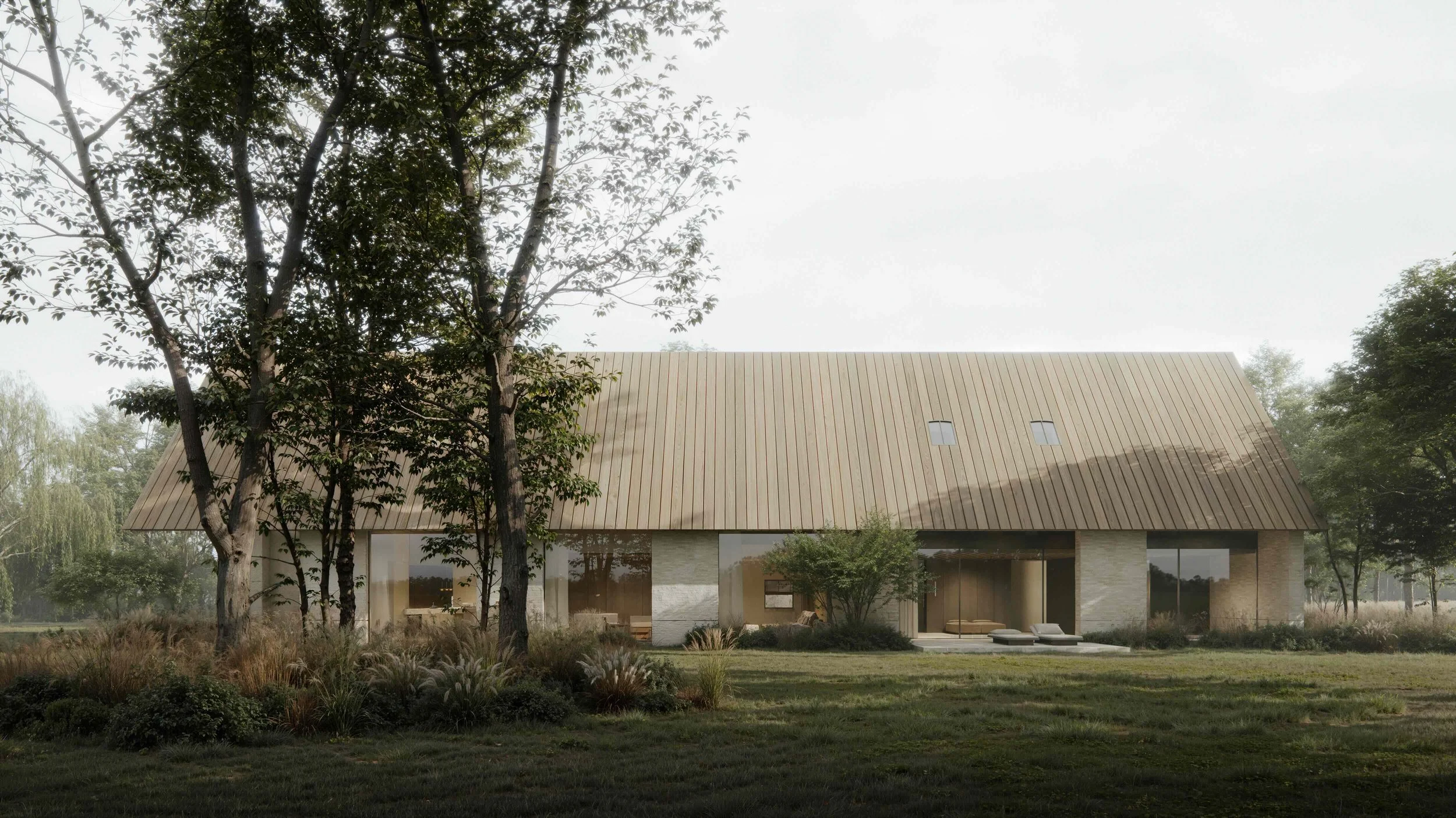 A modern house with a sloped metal roof, large windows, and a patio surrounded by grass and trees under a cloudy sky.