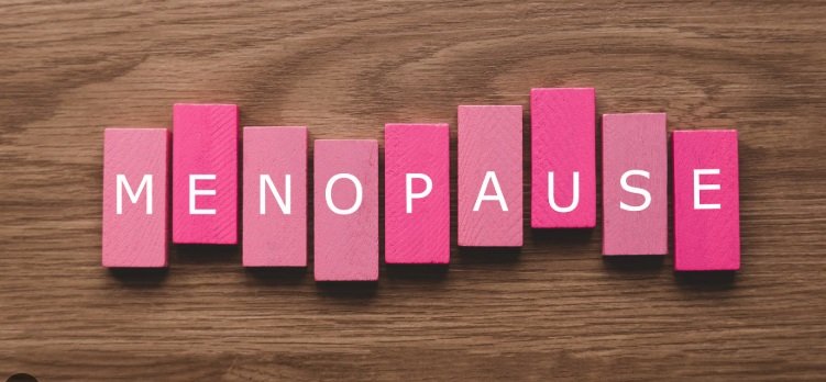 Pink wooden blocks spelling out "Menopause" on a wooden surface.