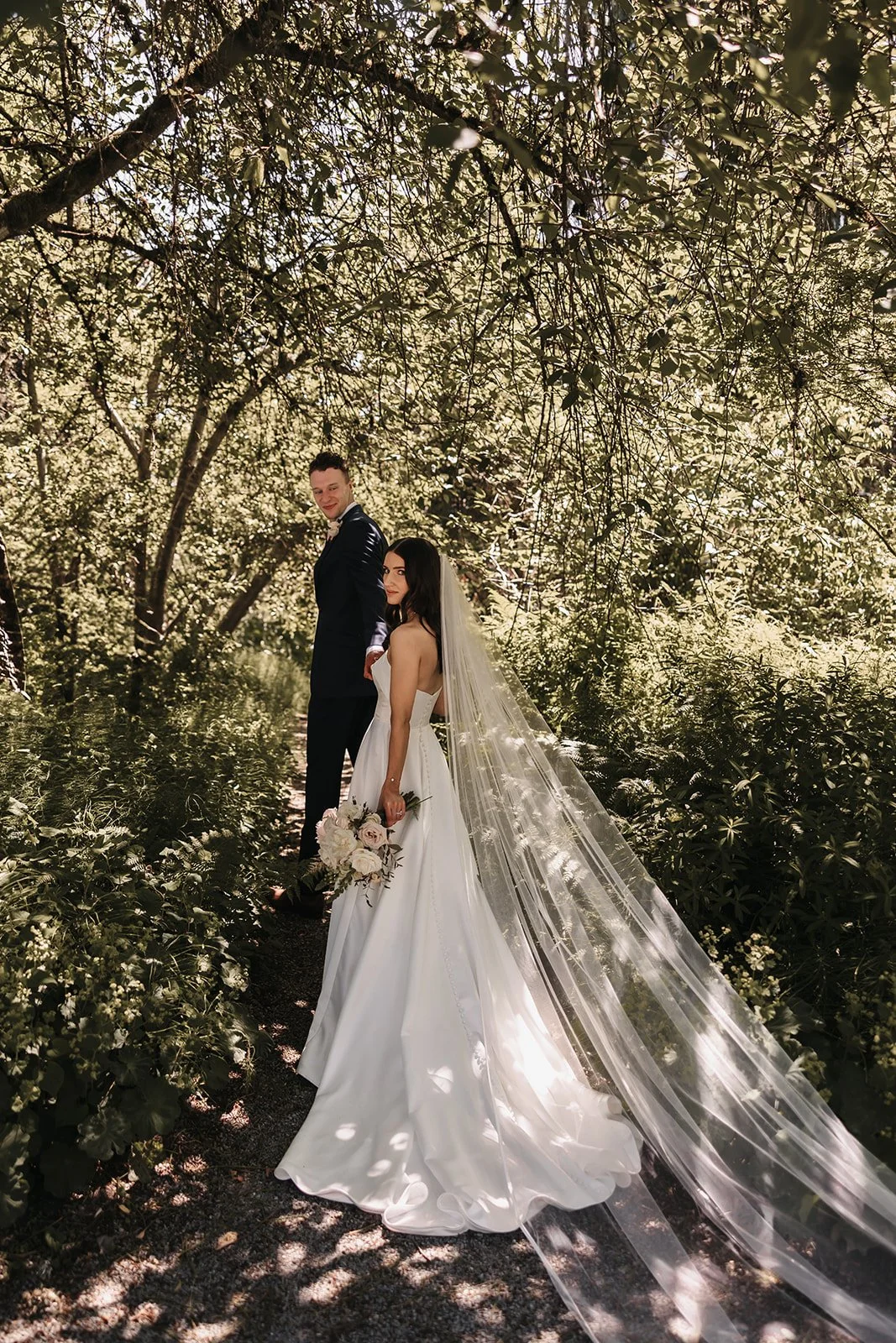 A bride and groom walking through a forest during their all-inclusive BC elopement