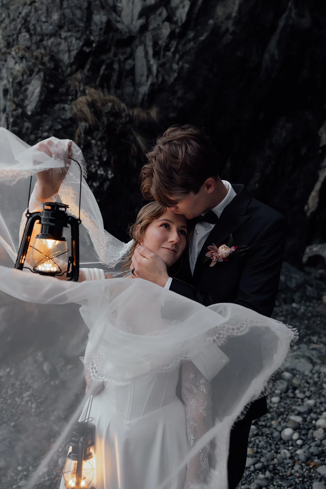 A newly eloped bride and groom in Tofino, holding lanterns while kissing