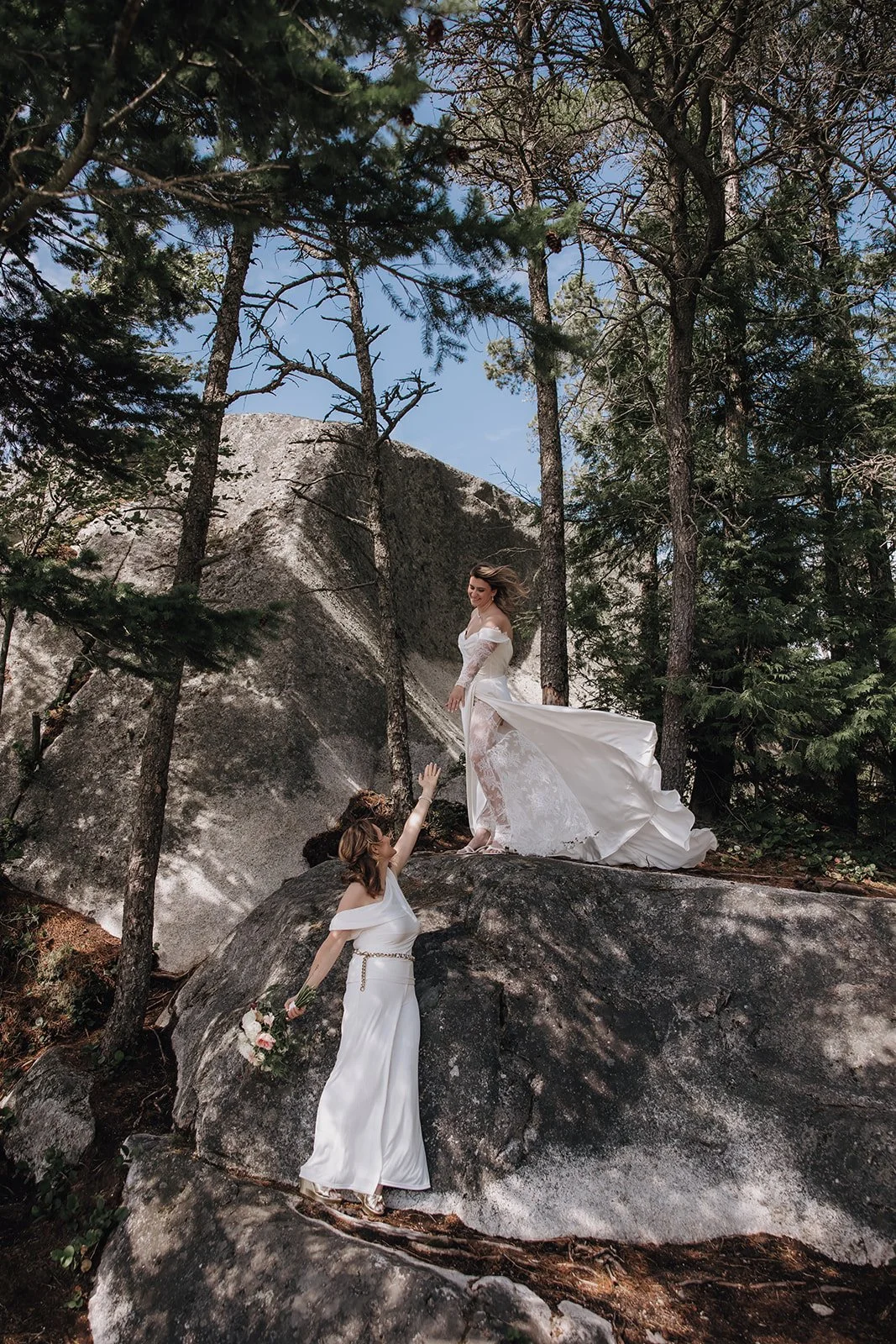 Brides reaching out to each other in the mountains of Squamish BC