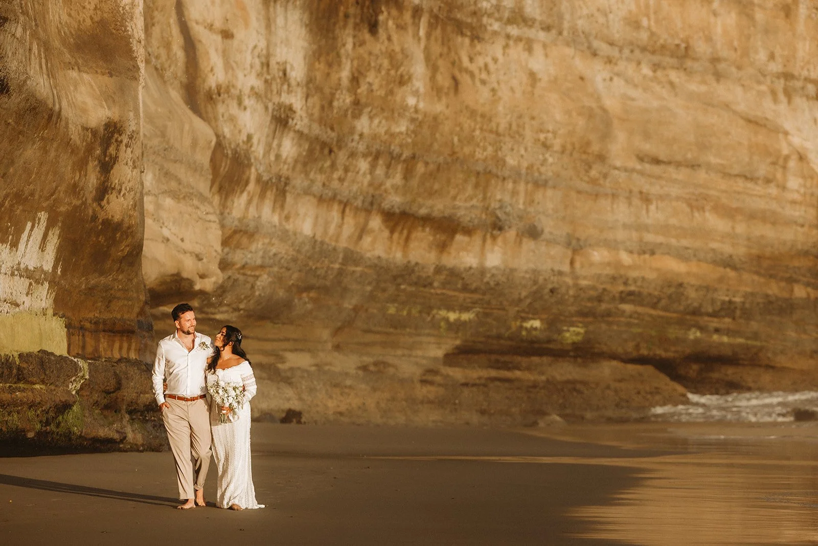 A bride and groom eloping along Mystic Beach