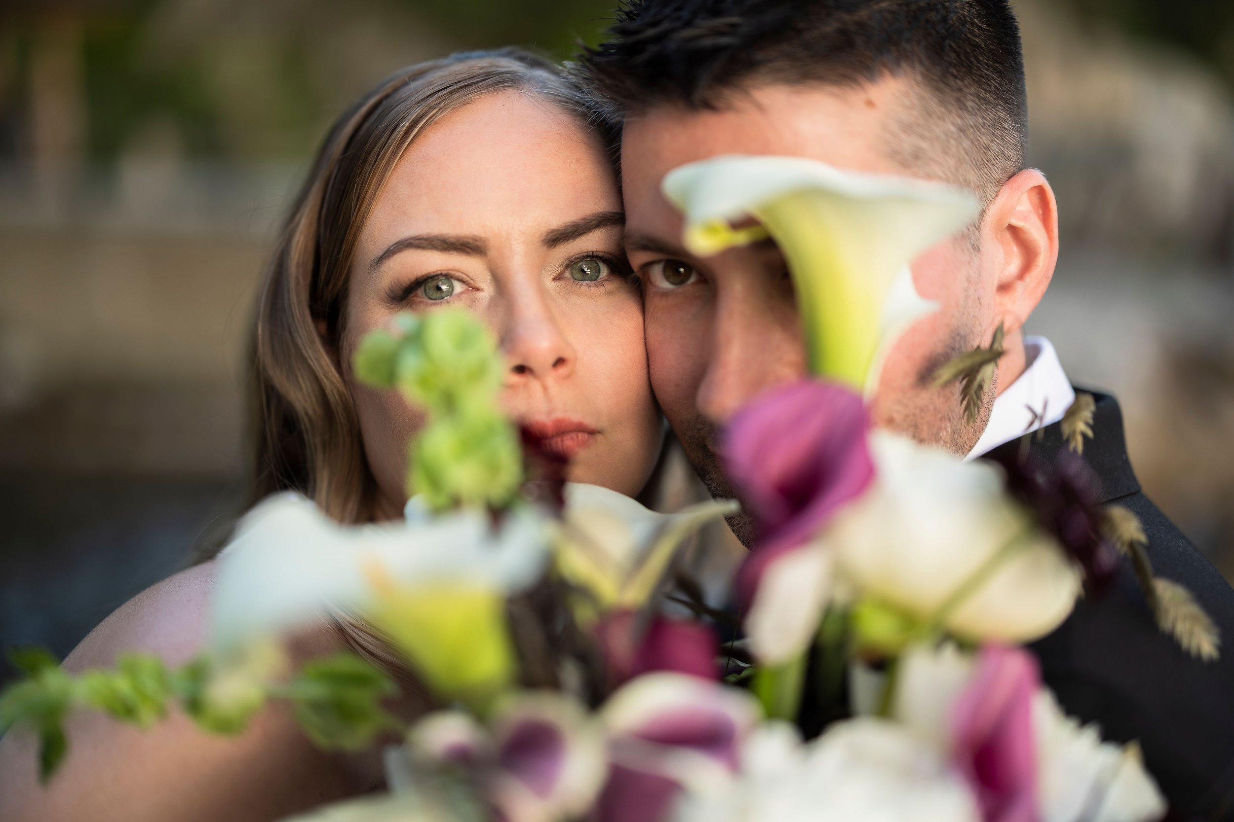 A bride and groom behind their wedding bouquet