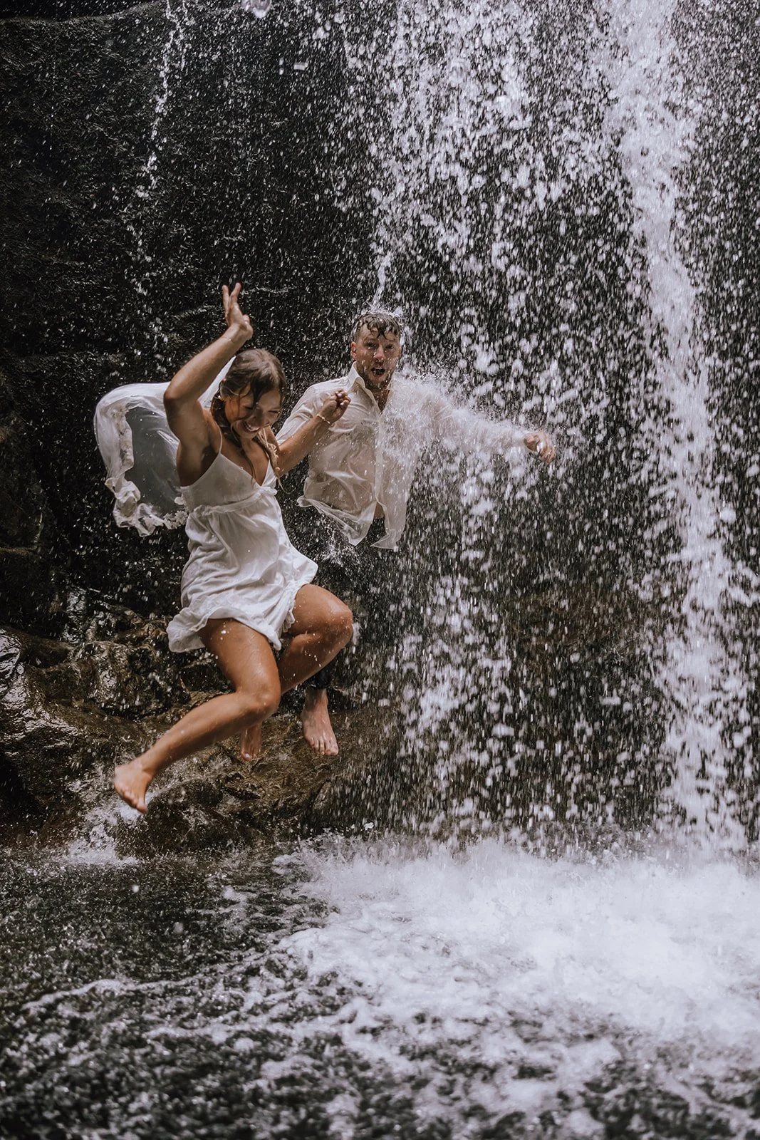 Bride and groom eloping, jumping through a waterfall in BC elopement.