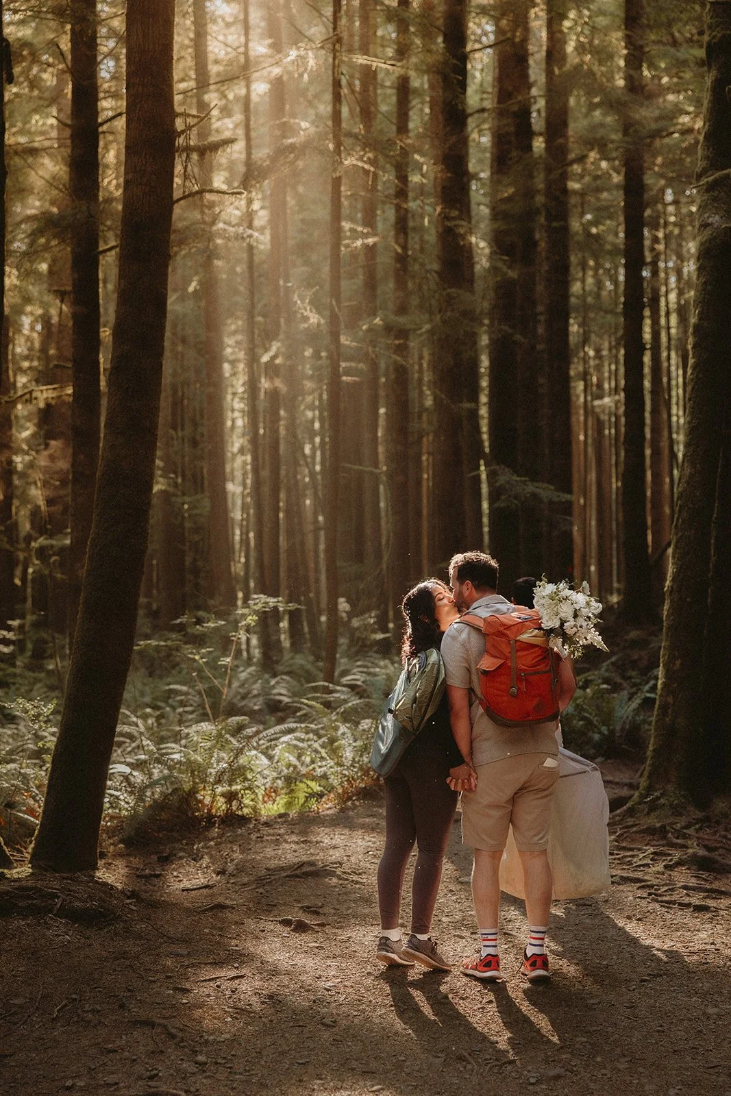 A couple kissing in a forest on their way to their elopement at Mystic Beach on Vancouver Island