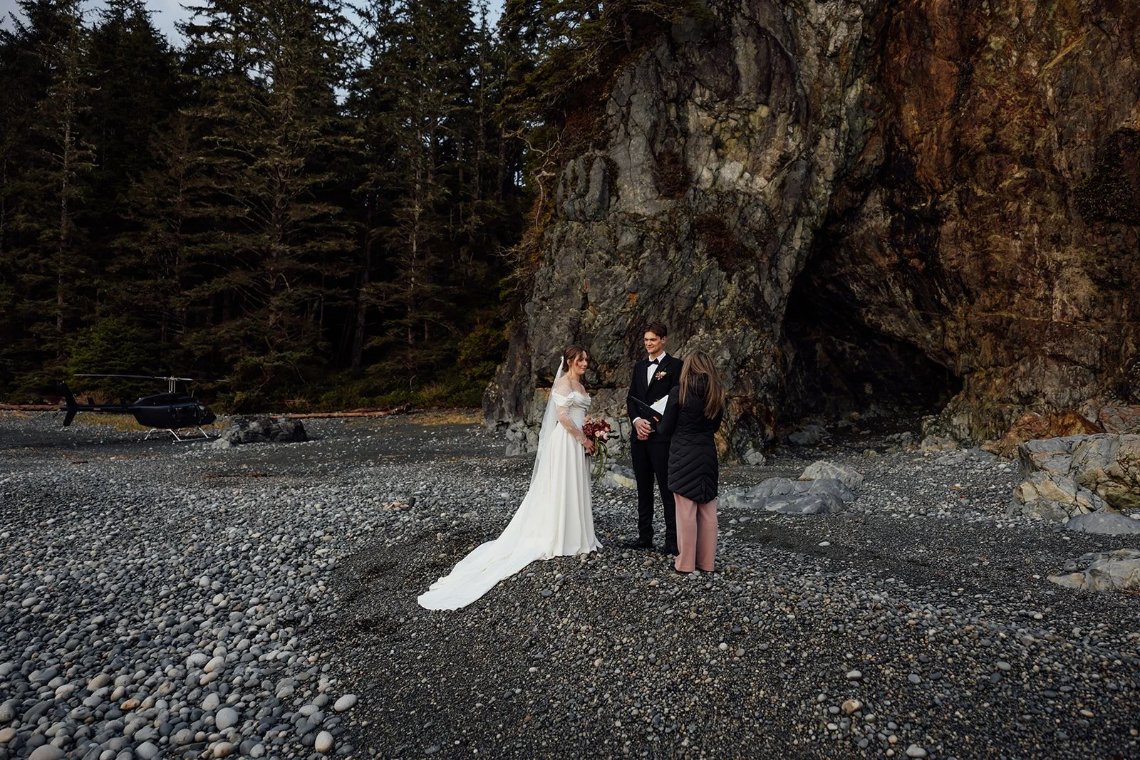 A bride and groom eloping on the Tofino beach, helicopter in the background
