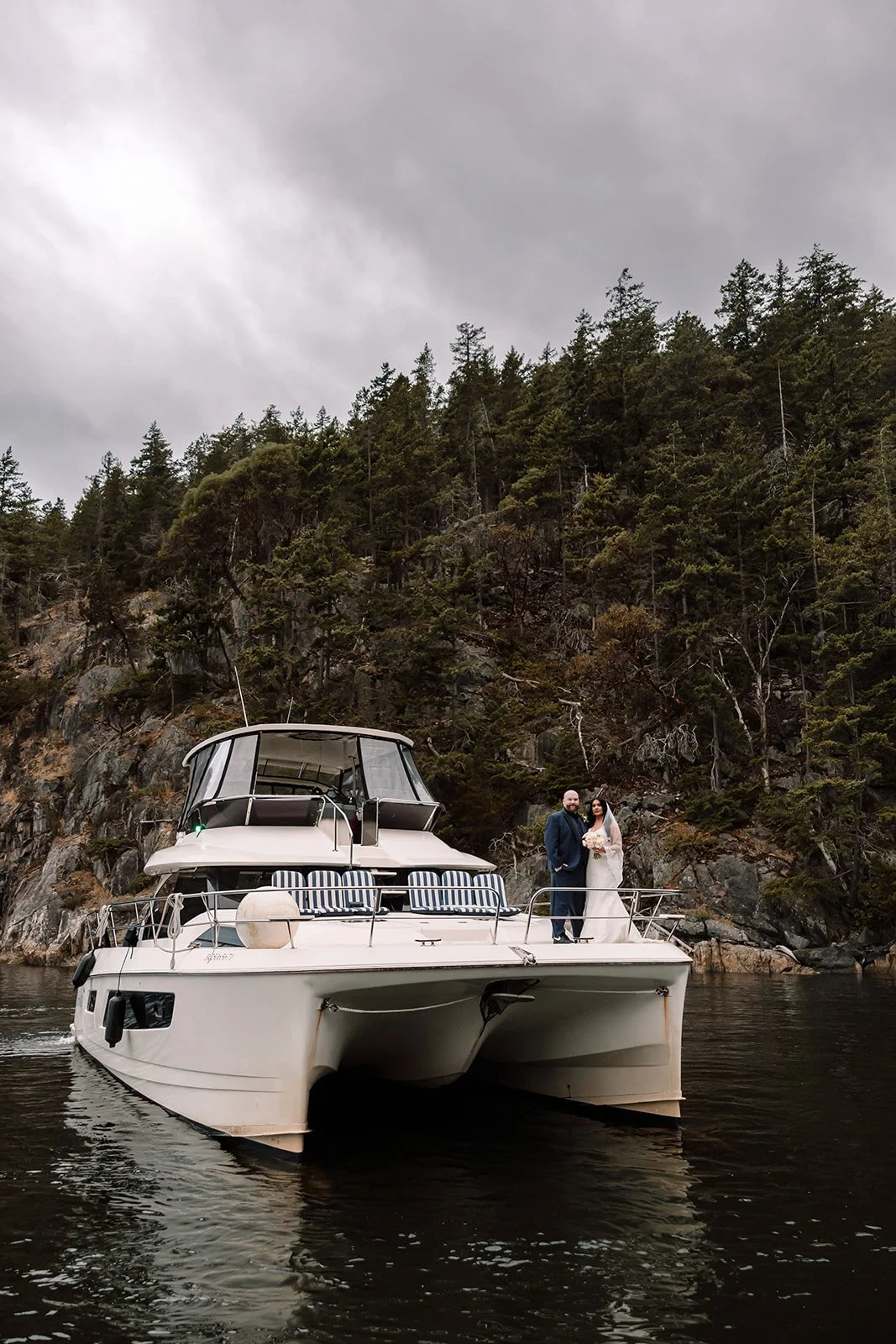 A bride and groom pose on a yacht near Granville Island in BC