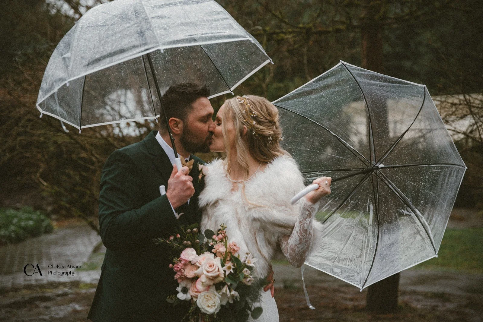 A bride and groom kissing under umbrellas as they elope
