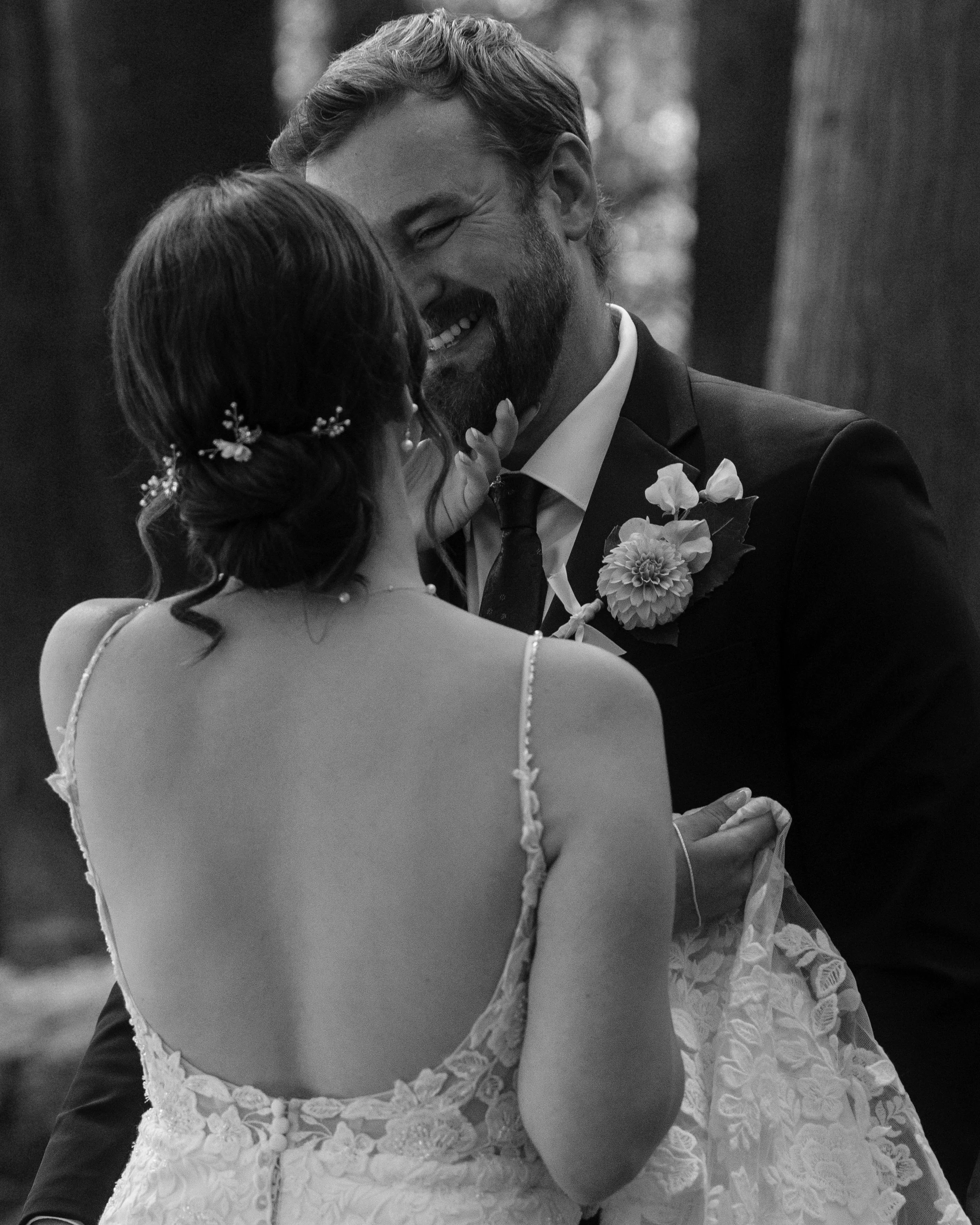 A black and white photo of a groom gazing into his bride's eyes