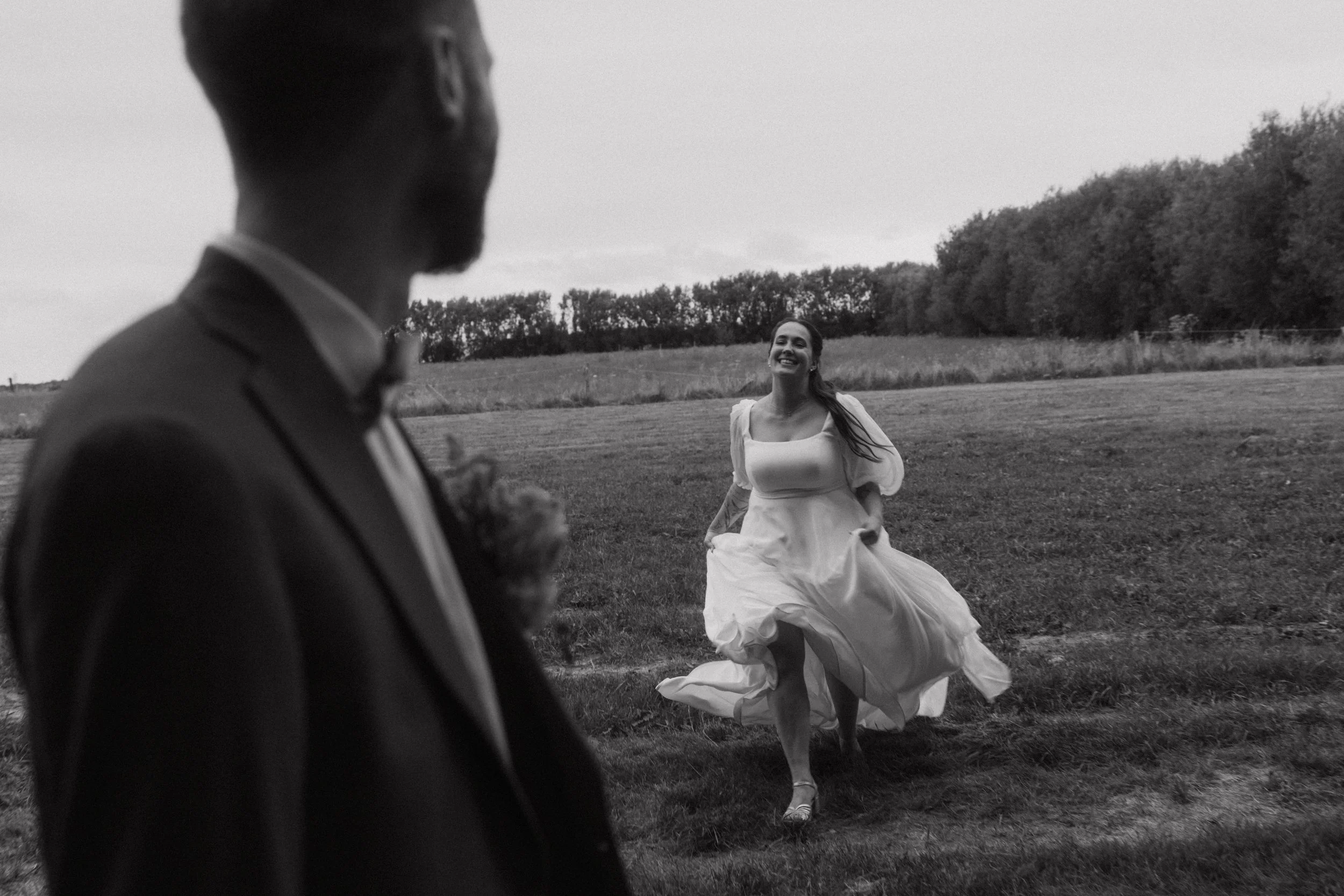 Timeless black and white shot of a bride running towards her waiting groom