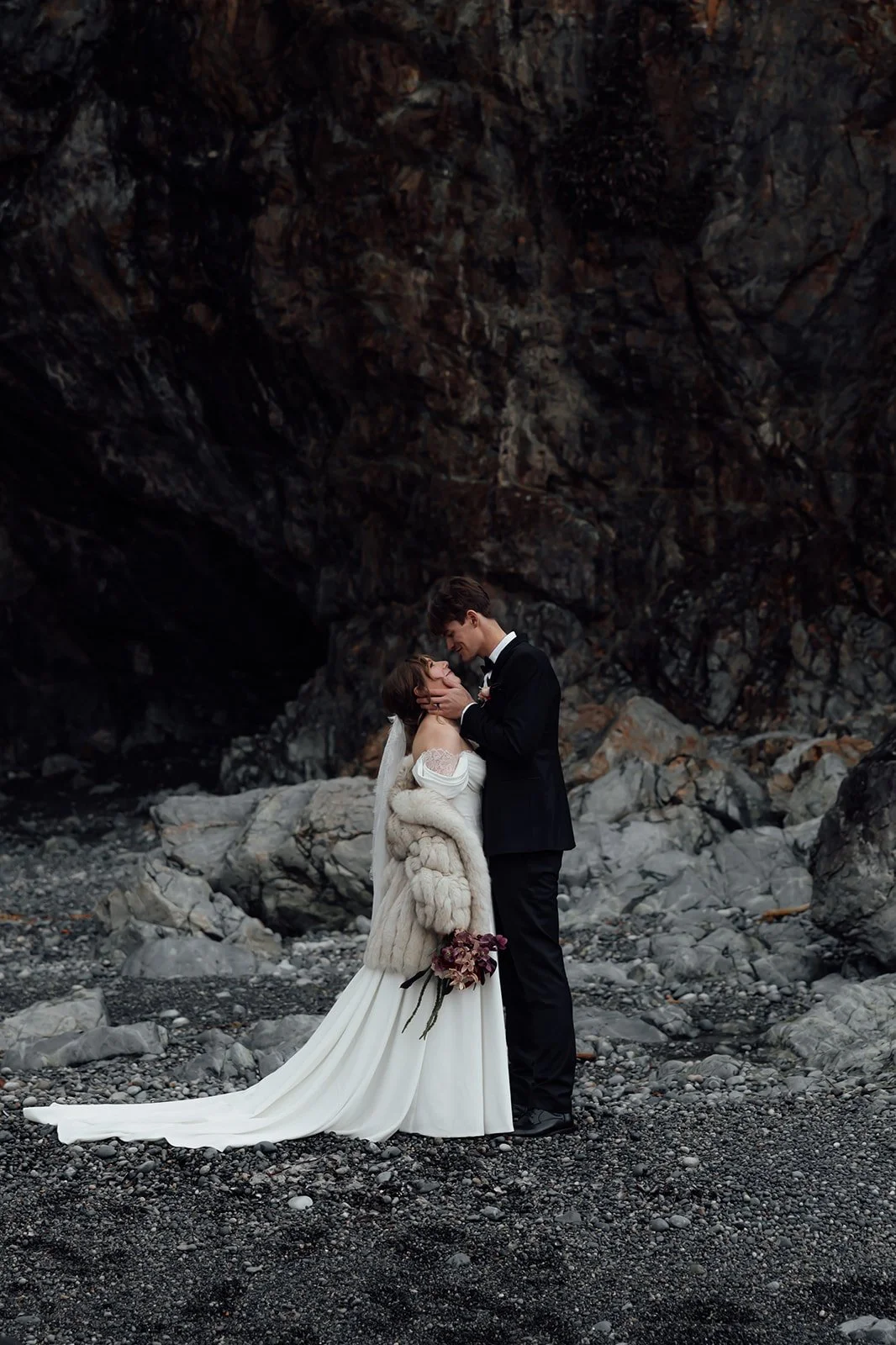 A bride and groom as they elope, gazing into each others eyes in front of the caves of Tofino