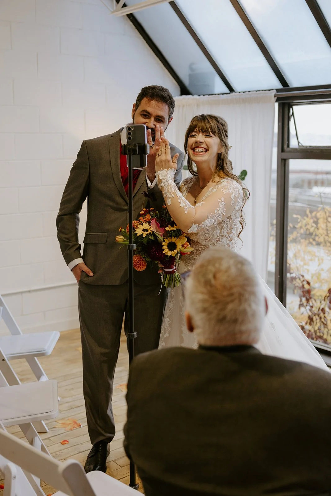 A bride and groom showing their rings to the camera