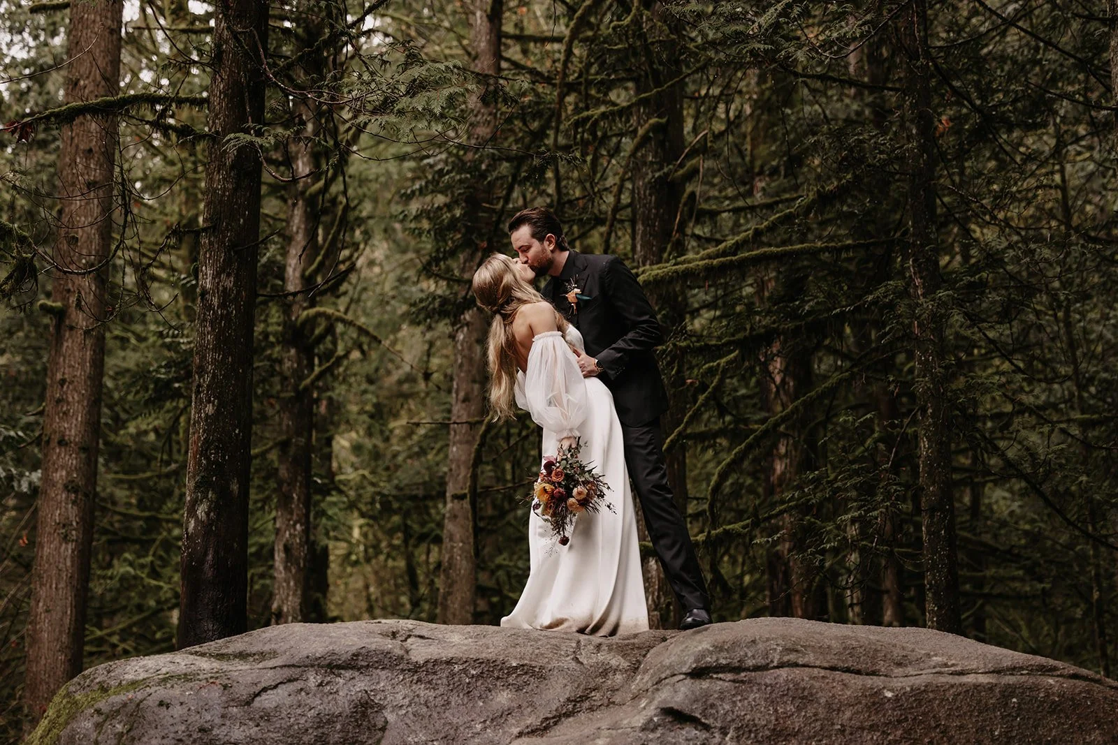 A bride & groom kissing in a magical forest in Lynn Valley, North Vancouver
