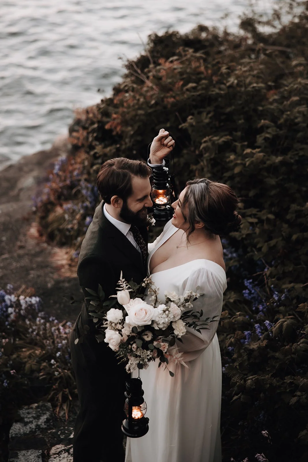Bride and groom holding a lantern in wildflowers during elopement in BC.