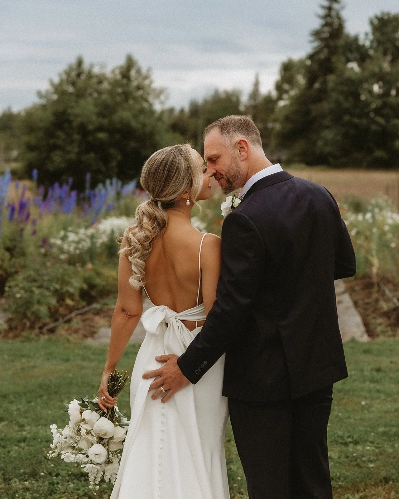 Romantic elopement moment in sunlit field of colorful flowers.
