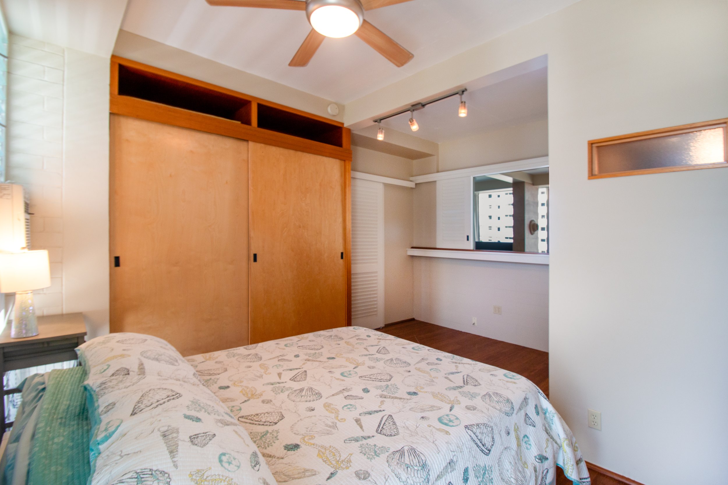 Bedroom with a custom-built closet and a window opening to the living area.