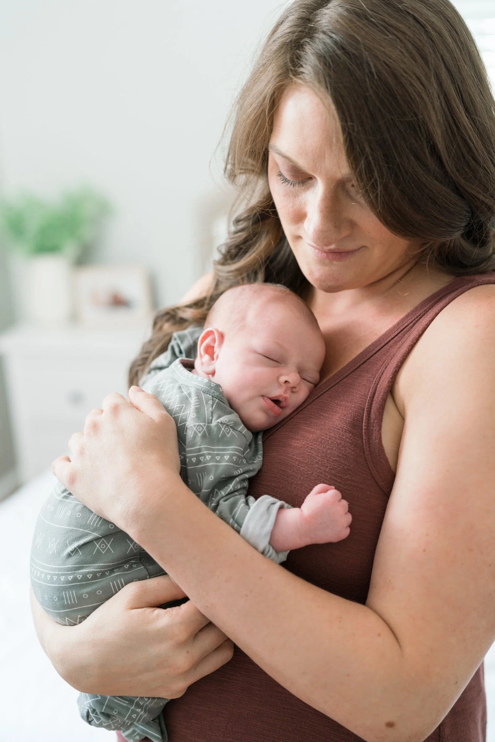 Oahu newborn photographer captures mom cradling sleeping baby in natural light—stress-free, quick sessions for relaxed families.